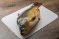 Live fish carp lies on a cutting board in the kitchen