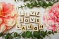 Live Love Laught alphabet letter with green leave and pink flower flat lay on marble background Royalty Free Stock Photo