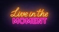 Live in the Moment neon lettering on brick wall background.