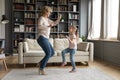 Lively aged grandmother dancing with little granddaughter at home