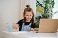 Lively little girl painting behing a table, smiling, showing missing teeth