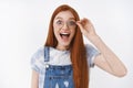 Lively redhead impressed happy girl wear denim overalls smiling amazed cheerful touch glasses look camera astonished and