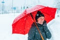 Lively woman talking on mobile phone under umbrella in snow