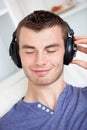 Lively young man listening to music on the couch