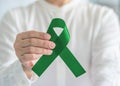 Liver Cancer and Hepatitis B disease awareness concept symbolic with emerald green or jade color ribbon in person`s hand Royalty Free Stock Photo