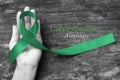 Liver Cancer and Hepatitis B - HVB Awareness month ribbon, Emerald Green Jade ribbon awareness color on helping hand Royalty Free Stock Photo