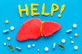 Liver diseases and treatment. Word help, organ and pills on blue background top view