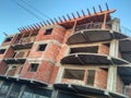 Living block construction site, concrete structure and brick walls, wood element for rooftop and blue sky on the background