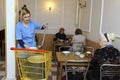 Living on a breadline. Social worker pouring soup in plate for poor old people sitting at a table of canteen