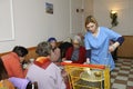 Living on a breadline. Social worker waitress pouring soup in plate for poor old people sitting at a table of municipal canteen