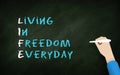 Living in Freedom Everyday : Life Acronym in Chalk Bored. Human Hand Writing text on Blackboard