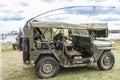 Living History reenactment - WW2 Jeep with antennas tied down and shovel secured to side - man in army uniform with painted face g