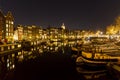 Houseboats reflecting in a canal in Amsterdam at night