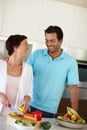 Living life the healthy way. a man standing beside his wife as shes chopping vegetables at the kitchen counter. Royalty Free Stock Photo