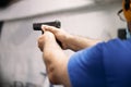 Living in a pandemic. A man in a medical mask aims at a target with a gun at a shooting range amid a pandemic. Royalty Free Stock Photo