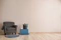 Living room with armchair, table and basket near light wall