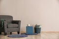 Living room with armchair, table and basket near light wall