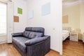 Living room with a balcony with white wooden shutters, a black leather