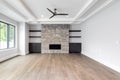 A living room with built in shelves and a rock fireplace.