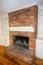 A living room or den with hardwood floors, white walls and a red brick fireplace with mantle in a newly renovated house Royalty Free Stock Photo