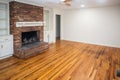 A living room or den with hardwood floors, white walls and a red brick fireplace with mantle in a newly renovated house Royalty Free Stock Photo