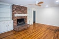 A living room or den with hardwood floors, white walls and a red brick fireplace with mantle in a newly renovated house Royalty Free Stock Photo