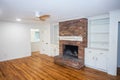 A living room or den with hardwood floors, white walls and a red brick fireplace with mantle in a newly renovated house Royalty Free Stock Photo