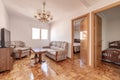 Living room with doors to other rooms and checkerboard parquet floor and three-seater sofa upholstered in fabric with wooden