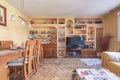 A living room full of wooden furniture with a built-in bookcase with niches, a dining table with matching chairs, a flat TV and Royalty Free Stock Photo