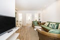 A living room furnished with a stained wicker sofa set with green cushions, a white tv table, tiled floors and a round white Royalty Free Stock Photo