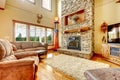 Living room with high ceiling, stone fireplace and leather sofa. Royalty Free Stock Photo