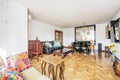 Living room of a house with mismatched wooden furniture of different styles and sofas of the same style, a mural of mirrors on one