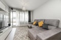 Living room of a house with a sofa with a chaise longue upholstered in gray velvet in front of a bookcase