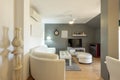 Living room of a house with a white leather sofa covering one wall and a dining table and a matching coffee table, flat tv on a Royalty Free Stock Photo