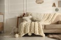 Cozy living room interior with beige sofa, knitted blanket and cushions Royalty Free Stock Photo