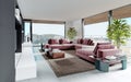 Living room with a large pink sofa and a TV unit with shelves and decor. Living room studio with kitchen and living area. Large