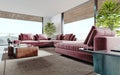 Living room with a large pink sofa and a TV unit with shelves and decor. Living room studio with kitchen and living area. Large Royalty Free Stock Photo