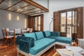 Living room of a loft-style house with balconies facing the street with brown shutters, stairs with metal steps and a green velvet