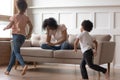 African mother sit on couch can`t handle with noisy kids