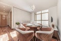 Living room of newly renovated apartment with wooden furniture with upholstered chairs, round dining table and large window on one Royalty Free Stock Photo