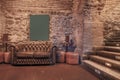 Living room of a nightlife venue with a shiny brown leather chester sofa, exposed stone and brick walls and stairs with indicative