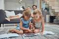 Living room, parents relaxing and children doing elearning on tablet in books on the floor in their home. Mother, father Royalty Free Stock Photo