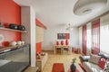 Living room with red decorative details, wooden dining table and window