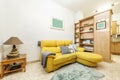 Living room of a rental house decorated with wooden furniture with a yellow chaise longue sofa and stoneware floors