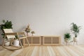 Living room with a rocking chair on the floor decorated with plant pots and a TV cabinet. and has a white concrete wall as a backg Royalty Free Stock Photo