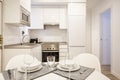 Living room with a round dining table with tableware set with crystal stemware and white crockery in an open plan kitchen with Royalty Free Stock Photo