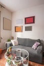 Living room with small gray sofa and circular metal and glass table on red tile floors Royalty Free Stock Photo