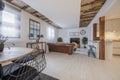 Living room of a studio apartment with open kitchen, exposed vintage wooden beams, brown leather chesterfield sofa and stoneware Royalty Free Stock Photo