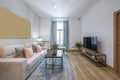 Living room of a vacation rental home with a three-seater sofa upholstered in beige fabric with silk cushions, a metal coffee Royalty Free Stock Photo