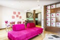 Living room of a vacation rental house decorated in purple tones with a chaise longue sofa, white dining table and bookcase with Royalty Free Stock Photo